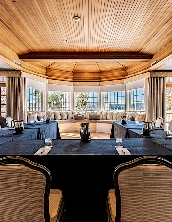 A conference room with a U-shaped table, elegant chairs, and large windows showcasing a scenic view.