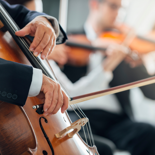 The image shows musicians playing string instruments: a close-up of hands playing a cello and blurred background of violinists.